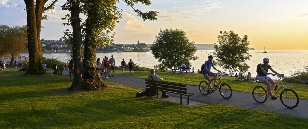 Young couple cycling, others walking or jogging late afternoon and enjoying the sunset